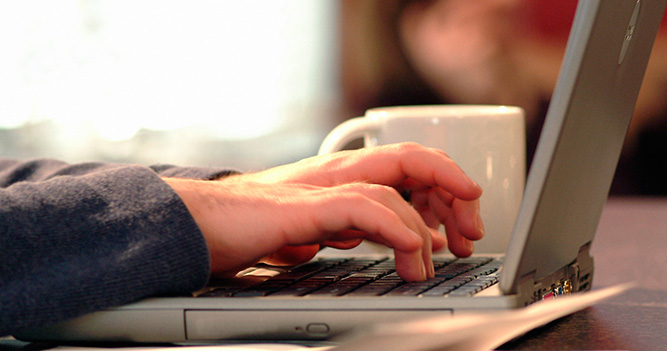 Closeup of hands typing on laptop as someone is studying online