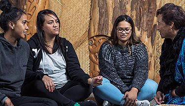 Group sitting on the floor of a marae having a conversation