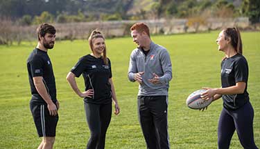 Students learning how to handle a rugby ball
