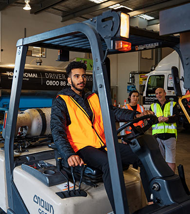 Student using a forklift while another student and tutor observe
