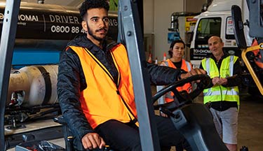 Student using a forklift while another student and tutor observe