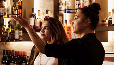 Student being taught by manager behind the bar