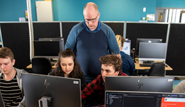 IT tutor with students at their computer