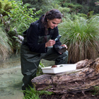 Environmental student examining a rock in a stream