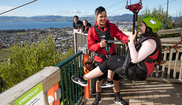Tourism and Travel student hooking a visitor onto a zipline Tourism and Travel student hooking a visitor onto a zipline