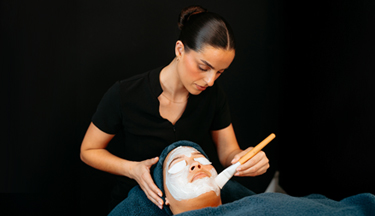 Beauty student applying a facial mask to client