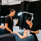 Beauty student with tutor applying a facial cream to client