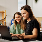 Students looking over their work on a laptop