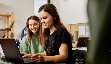 Students looking over their work on a laptop