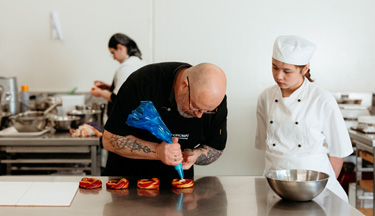 Baking tutor showing student how to pipe