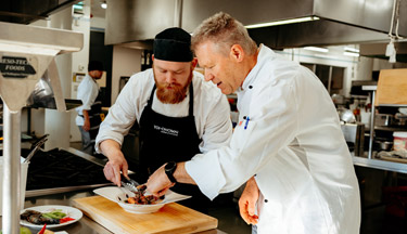 Culinary student with tutor plating up food