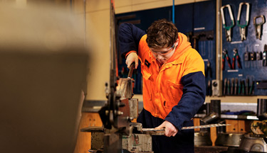 Engineering student using a guillotine to cut a sheet of metal