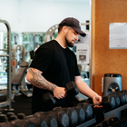 Gym user picking up dumbbells
