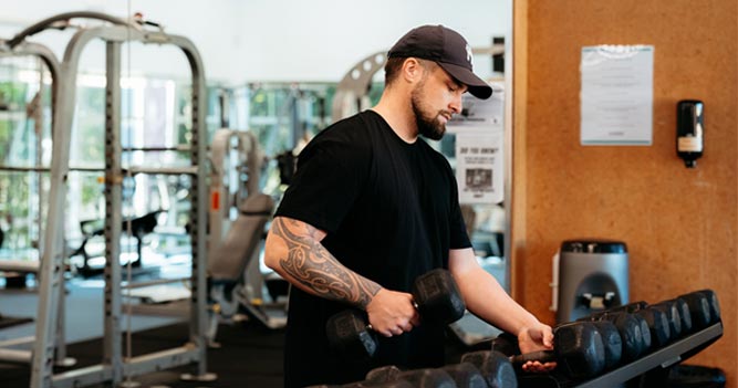 Gym user picking up dumbbells
