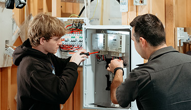 Electrical student with tutor going through some wiring 