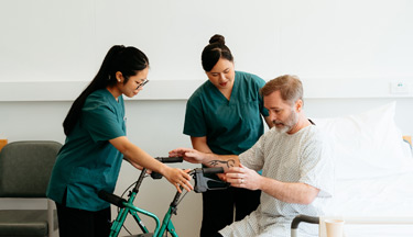 Healthcare Assistants helping a patient to stand